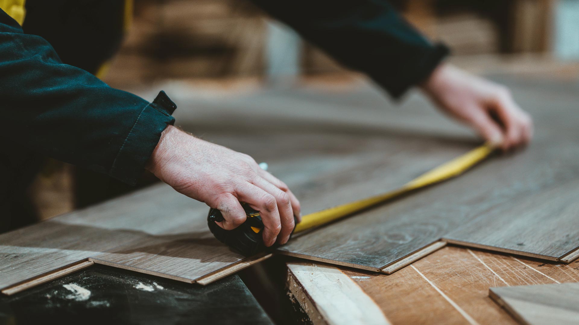 Carpenter measuring a plank of laminate flooring.